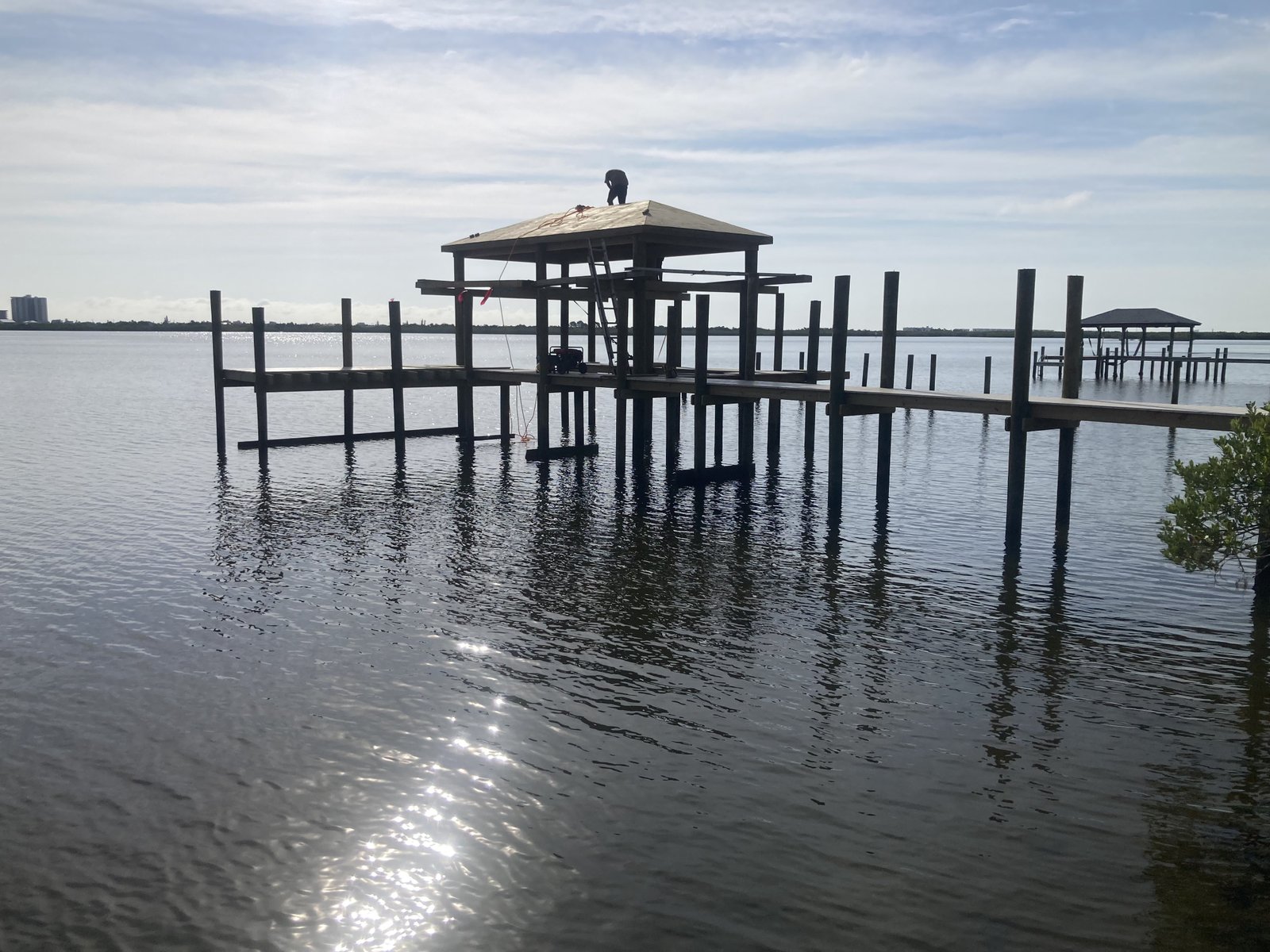 Crew installing covered boathouse roof over open water dock, Florida